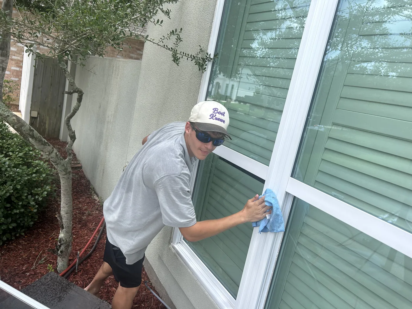 Boot Krewe Cleaners technician hand detailing a pane with a microfiber cloth