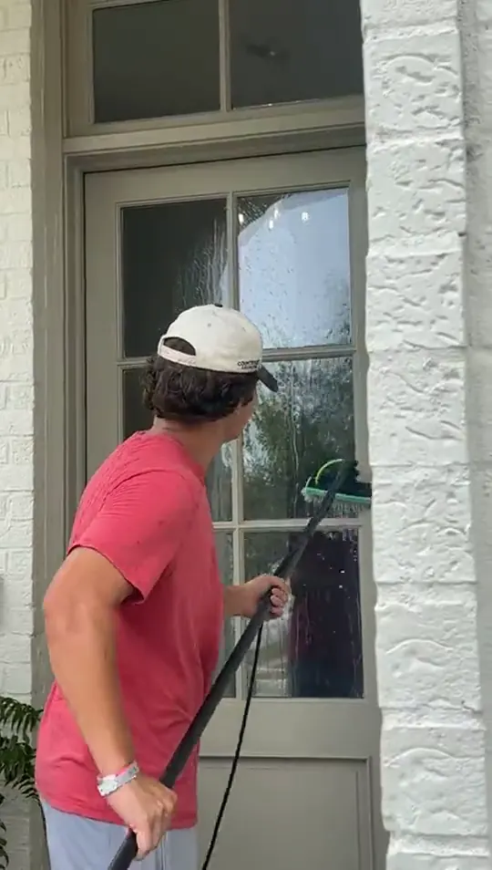 Technician cleaning the glass of a front door with a water fed pole