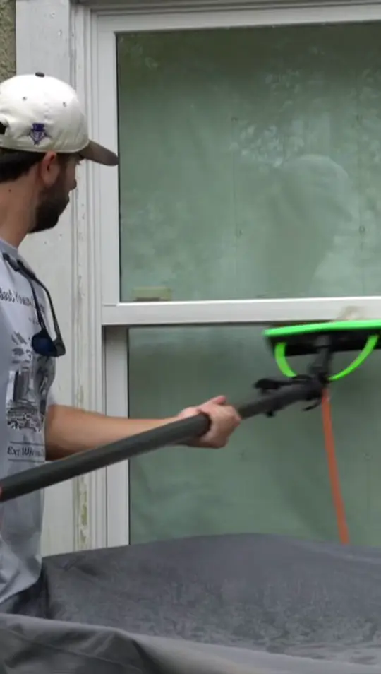 Boot Krewe technician running the pure water brush across a sash window with the screen taken off and set aside