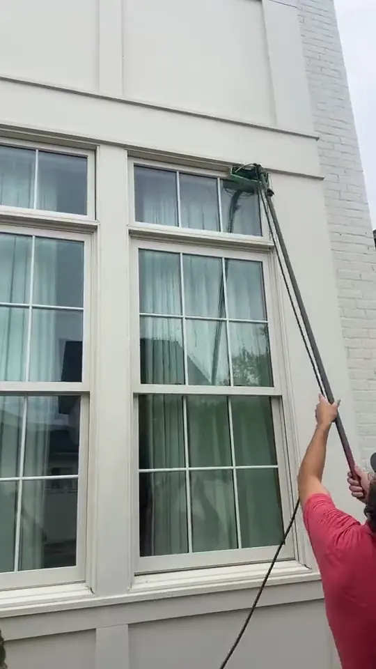 Water fed brush running down a tall sash window
