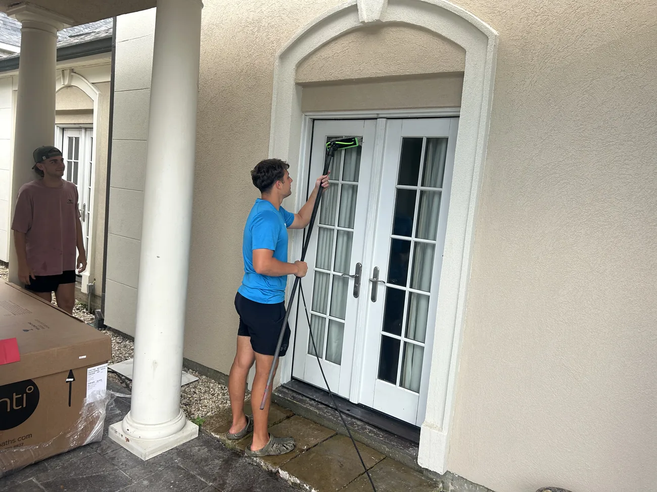 Boot Krewe technician cleaning glass French doors at a front entry